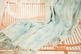 Hand woven African indigo textile throw with variegated denim blue and cream tones, soft fringed edge.