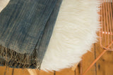 Folded denim blue Mossi Indigo African textile throw, revealing its textured weave and fringe.