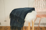 Textured fringed edge of a hand-woven vintage indigo African textile throw.