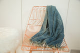 Vintage denim indigo African textile throw draped, with hand woven texture and frayed edges.