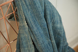 Hand woven denim mossi indigo textile, displaying varied blue hues and subtle stitched lines.
