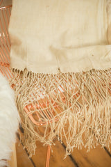 Close-up of hand-woven natural African textile's edge with flowing tassels.