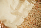 Natural hand woven African textile throw, showing supple texture, subtle patina, and long tassels.