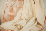 Supple, natural hand woven cotton African textile throw draped with subtle texture.
