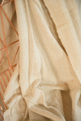 Close-up of natural cream hand woven African cotton textile with raw edge.