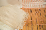 Fringed edge of a natural hand woven African collectible textile, showing subtle texture.