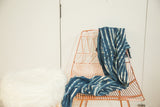 Collectible hand-woven African indigo textile throw, draped with blue and white stripe patterns.