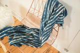 Hand-dyed African indigo textile with varied blue and off-white stripe patterns.