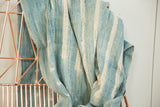 Hand-woven African indigo textile with varied blue and cream batik stripes.