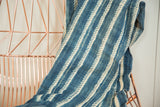 Close-up of hand-dyed African indigo textile showing textured cream stripes.