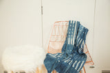 Draped vintage indigo African textile throw, showcasing unique hand-dyed batik patterns.