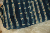 Folded vintage African indigo textile showing varied hand-dyed stripe and arrow patterns.
