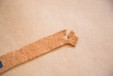Felt flag banner end, showing its frayed edges and tan, time-worn texture.
