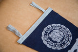 Close-up of the Kings Point felt flag's gray binding, hanging loops, and white crest detail.