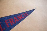 Vintage blue felt pennant tip showing red 'FRANCIS' lettering and aged texture.