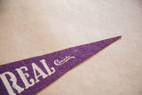 Purple felt pointed end of a Montreal Canada pennant, showing white 'REAL Canada' text.