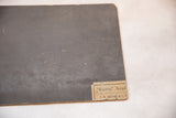 Reverse of the vintage painting board, charcoal gray with surface chips and a maker's label.