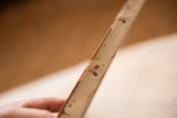 Close-up of antique oil on canvas painting's side edge, showing aged texture and marks.
