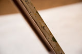 Antique painting's canvas edge, with visible tacks and aged, paint-speckled surface.
