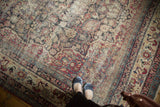 Antique Kermanshah carpet detail, scrolling florals in cochineal red, navy, camel, with soft pile wear.