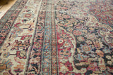 Scrolling floral design elements and geometric borders on an antique Kermanshah carpet.
