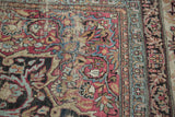 Cochineal red, blue, and camel floral design on antique Kermanshah carpet, showing even wear.