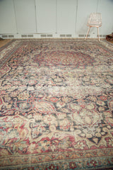 Antique Kermanshah carpet with scrolling floral patterns, cochineal red, navy blue, and faded pile.
