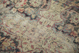 Faded red and blue floral motifs on antique Kermanshah carpet, with visible foundation wear.