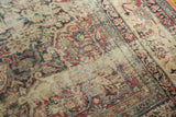 Antique Kermanshah rug's scrolling floral pattern in cochineal red, blue, and camel, showing mostly even wear.