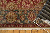 Distressed vintage Agra carpet border with faded red, teal, gold floral patterns and fringe.
