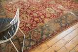 Detail of distressed vintage Agra carpet: faded cinnabar red field, gold floral patterns, teal border.