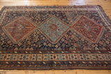 Antique Kamseh rug's main border, serrated medallion contours, with rich reds and deep blues.