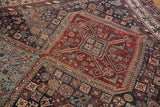 Detail of antique Kamseh carpet: serrated madder red medallion, dense navy, and sky blue motifs.