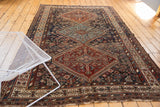 Antique Kamseh carpet corner with a rich red serrated medallion and intricate floral-geometric border.