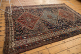 Antique Kamseh rug corner, displaying red, navy, and ivory geometric border patterns and fringe.