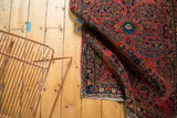 Vintage American Sarouk detail: cherry red ground, navy border, floral tendrils, and end fringe.