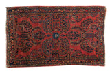 Classic American Sarouk rug with cherry red ground, central blue palmette, and floral vinery.