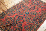 Vintage American Sarouk rug featuring red ground, blue scrolling vinery and floral bouquets.
