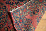 Vintage American Sarouk rug's hard tatter on folded edge, revealing red and blue floral motifs.