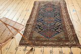 Geometric antique ivory border frames deep indigo field with Herati pattern.