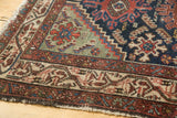 Vintage Hamadan runner corner, detailed geometric borders in red, indigo, and green, with tattered fringe.