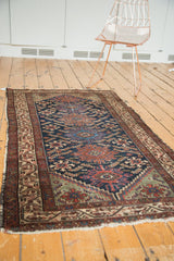 Vintage Hamadan runner corner showing serrated Herati leaves, indigo field, and tattered fringe.