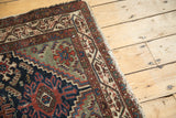 Vintage Hamadan runner corner showing tattered fringe, exposed foundation, and geometric border.