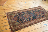 Geometric serrated leaves, pinwheels on indigo field, and madder red Hamadan rug border.