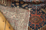Exposed woven foundation and hand-knotted pile with indigo and madder red geometric motifs.