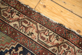 Hamadan rug edge, tattered with geometric madder red, antique ivory, and indigo patterns.