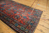 Vintage Lilihan rug corner with brick red field, blue floral tendrils, and aged patina.