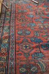 Secured side selvage of the Lilihan rug, showing brick red field and blue floral tendrils.