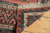Vintage Caucasian Soumac flat-weave rug corner with zig-zag border, macram fringe, blush, blue, and brown.