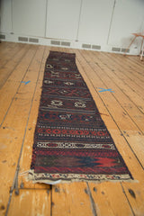 Angled view showcasing the full length of the narrow antique Belouch Soumac runner.